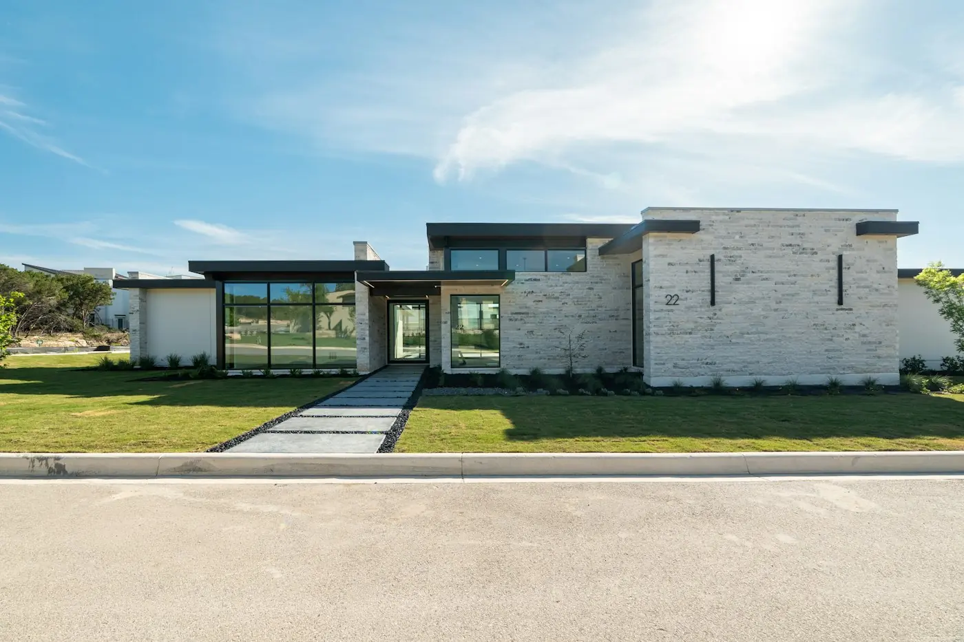 Contemporary stone house with large windows and a wide green lawn